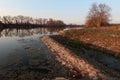 Spring evening landscape with large shallow fishing pond, spillway channel on the right bank and tree lanes on both banks. Royalty Free Stock Photo