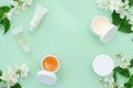 Spring facial care. jar, tube with cream, cosmetic product with jasmine flowers on green background. natural herbal organic cosmet Royalty Free Stock Photo