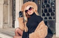 Spring fashionable female accessories clothes. Stylish blonde woman in teddy coat hat and holding handbag outdoors Royalty Free Stock Photo