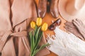 Spring female outfit with yellow tulips. Set of clothes, shoes and accessories on orange background