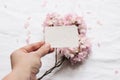 Spring feminine wedding stationery mockup scene. Closeup of woman hand holding blank cotton paper card. Defocused