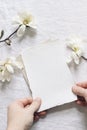 Spring feminine wedding stationery mockup scene. Closeup of woman hands holding blank cotton paper card. Blooming white Royalty Free Stock Photo