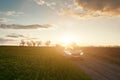Spring field and car on dirt road at sunset Royalty Free Stock Photo