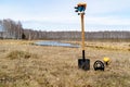On the spring field, a shovel and a metal detector lying on it are thrust into the ground, zdanya plan the lake and forest