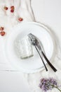 Spring floral table settings with spring flowers. Top view. Plates, wine glass and cutlery with decorative textile on white wooden