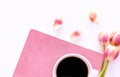 Pink tulips, coffee cup and pink notebook over white wbackground in a flat lay composition