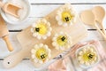 Spring flower shaped lemon tarts with bees, top view table scene against white wood