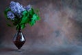 Bouquet of lilac in glass vase. Spring flowers on artistic backdrop. Copy space. Royalty Free Stock Photo