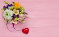 Spring flowers bouquet with decorative heart on pink wood background Royalty Free Stock Photo