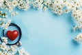 Spring flowers frame surrounding stethoscope and heart on blue background Royalty Free Stock Photo