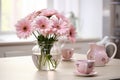 Spring flowers in glass vase on wooden table. Blurred kitchen background with old chair. Bouquet of pink gerberas