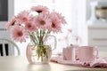 Spring flowers in glass vase on wooden table. Blurred kitchen background with old chair. Bouquet of pink gerberas