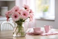 Spring flowers in glass vase on wooden table. Blurred kitchen background with old chair. Bouquet of pink gerberas