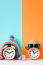 Spring forward fall back concept. Alarm clocks dressed in winter and summer accessories. Summer hat and glasses and winter hat as Royalty Free Stock Photo