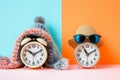 Spring forward fall back concept. Alarm clocks dressed in winter and summer accessories. Summer hat and glasses and winter hat as Royalty Free Stock Photo