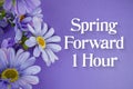 Spring Forward 1 Hour Daylight Savings Time message with bunch of flowers on purple background Royalty Free Stock Photo