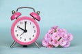 Spring forward, springtime, daylight saving time, pink alarm clock and flowers on a blue background Royalty Free Stock Photo