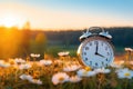 Spring forward. Time change in spring. Daylight saving time. Alarm clock on beautiful nature background with green grass Royalty Free Stock Photo