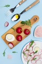 Spring fresh salad of radish, arugula and eggs, ingredients and cooking on blue background with shadow in sunlight.