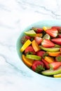 Spring fruit salad with strawberries, green apple, orange, lime, spinach leaves, and lemon in dish isolated on white table Royalty Free Stock Photo