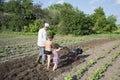 Spring in the garden man plowing land motor-block small son and Royalty Free Stock Photo