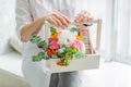 Spring gift in the hands of women. Flower arrangement in a white wooden box. Cakes with almond cookies, green branches, Rowan,