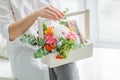 Spring gift in the hands of women. Flower arrangement in a white wooden box. Cakes with almond cookies, green branches, Rowan,