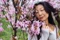 portrait of tender asian woman at sakura flowers background. Hanami celebration in sakura blooming garden