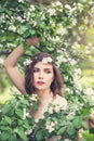 Spring girl face. Pretty young model woman in spring flowers wreath on floral background outdoor