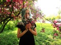 Spring girl with green hair stands under blooming cherry tree, which blooms