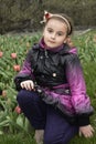 Spring girl sits in the meadow near the tulips.