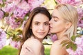 Spring girls face. Beautiful sensual sexy woman in pink flowers in summer blossom park. Lesbian couple kissing. Sensual Royalty Free Stock Photo