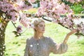 Spring girls in flowers. Beautiful woman in cherry blossom garden on a spring day, flower petals falling from the tree. Royalty Free Stock Photo