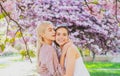 Spring girls in flowers. Outdoor portrait of young beautiful happy smiling female couple posing near flowering tree. Royalty Free Stock Photo