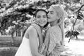 Spring girls in flowers. Outdoor portrait of young beautiful happy smiling female couple posing near flowering tree. Royalty Free Stock Photo