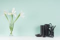 Spring green mint menthe interior of office with black stationery, books, fresh white iris bouquet in transparent glass vase.