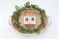 Spring green wreath of leaves rests on a wooden bamboo tray. Boxwood wreath. Flat lay, top view, copy space. Wooden block calendar