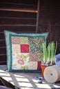 Spring handmade patchwork cushion with narcissus bulbs on wooden table