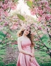 Spring happy woman walks in blooming sakura flowers garden. Medieval girl, blonde lady. pink silk dress. fairy image art