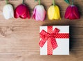 Spring is here. Gift box and tulips on wooden background