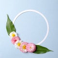 Spring holiday concept. Creative layout made of colorful flowers with green leaves and blank circle-shaped paper card outline on