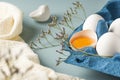Spring holiday Easter concept. Broken egg with yolk in the shell. Close-up of fresh chicken eggs in eco-packaging on a blue Royalty Free Stock Photo