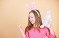 Spring holiday. Little girl holding Easter egg and bunny. Cute child with Easter rabbit bringing egg in spring. Small