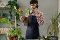 Spring houseplant care, repotting houseplants and consultation. Man calling on mobile phone while transplanting plant Royalty Free Stock Photo