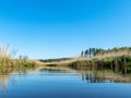 Spring landscape with a beautiful calm river, green trees and grass on the river bank, peaceful reflection in the river water