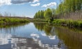 Spring landscape with a beautiful calm river, green trees and grass on the river bank, peaceful reflection in the river water