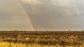 Spring landscape with double rainbow over burned field after thunderstorm. Beautiful natural background