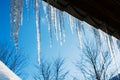 Spring landscape with ice icicles hanging from roof of house. Royalty Free Stock Photo
