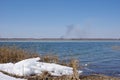 Spring landscape with a lake overgrown with reeds near the coast covered by white snow and a clear sky Royalty Free Stock Photo