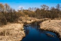 Spring landscape with a small river and yellow banks with dry grass Royalty Free Stock Photo
